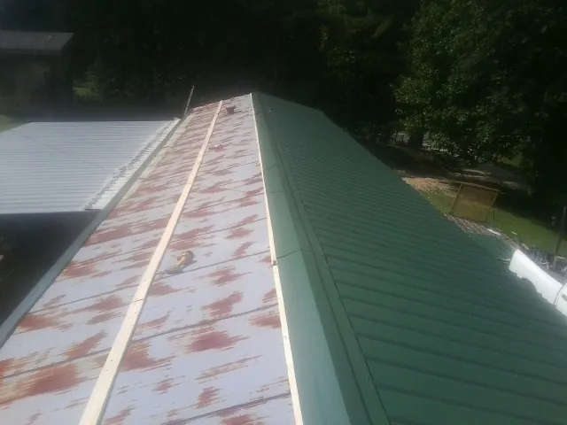 Old rusted panels beside newly installed green metal roofing — Wind Damage Roof Repair by Roofing Brothers in Garden Valley