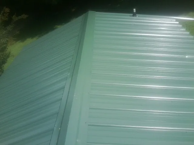 New green metal panels meeting at the ridge of a roof — Flat Roof Repair work by our crew in Garden Valley