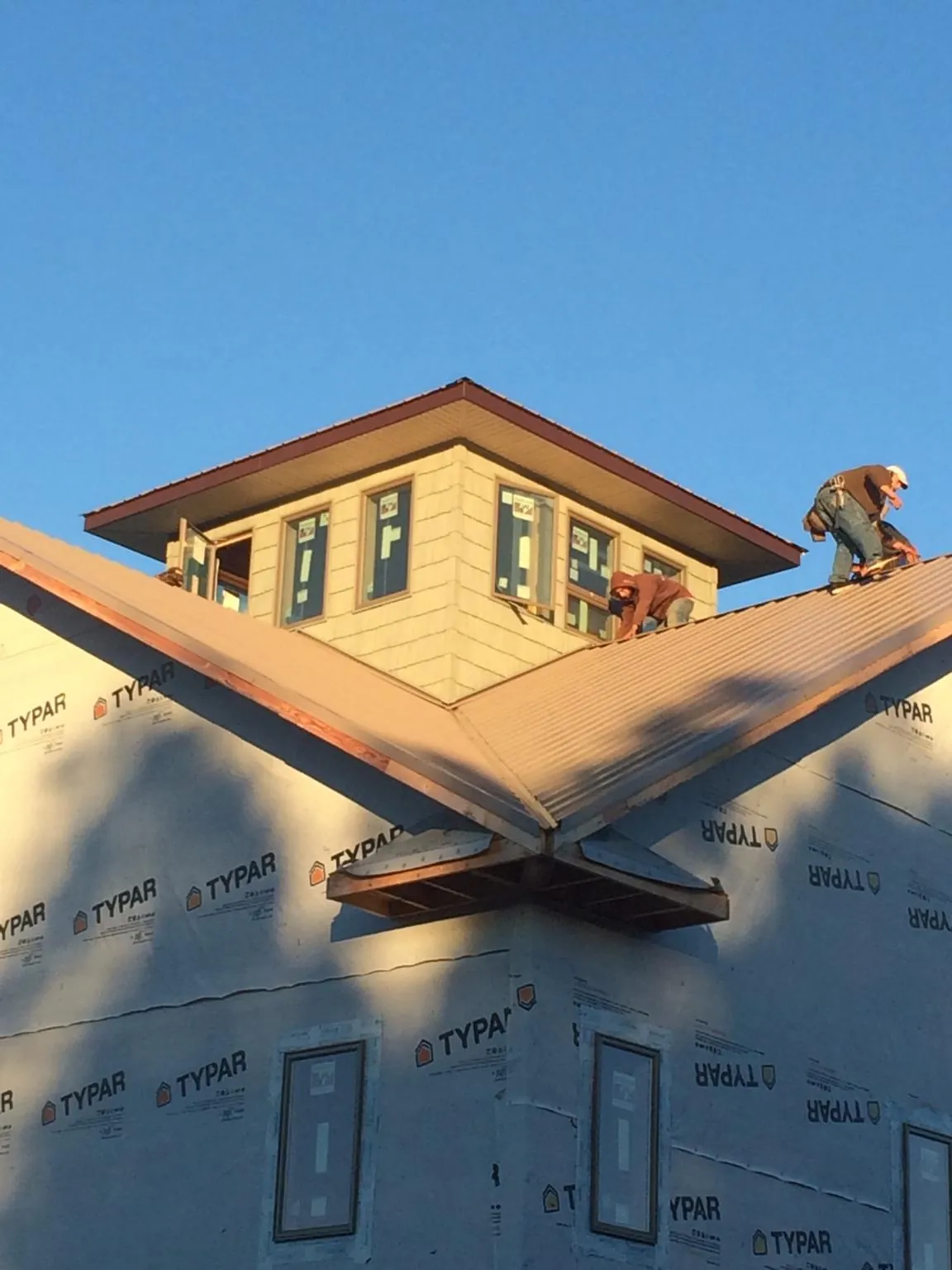 Roofers working around a rooftop cupola on a new metal roof at sunset — Roof Waterproofing in Garden Valley by Roofing Brothers